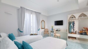 A hotel room with two beds, a desk, a chair, a TV, and a wardrobe.