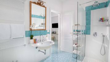 Uma casa de banho moderna com lavatório branco, cabine de duche em vidro e chão com padrão azul.