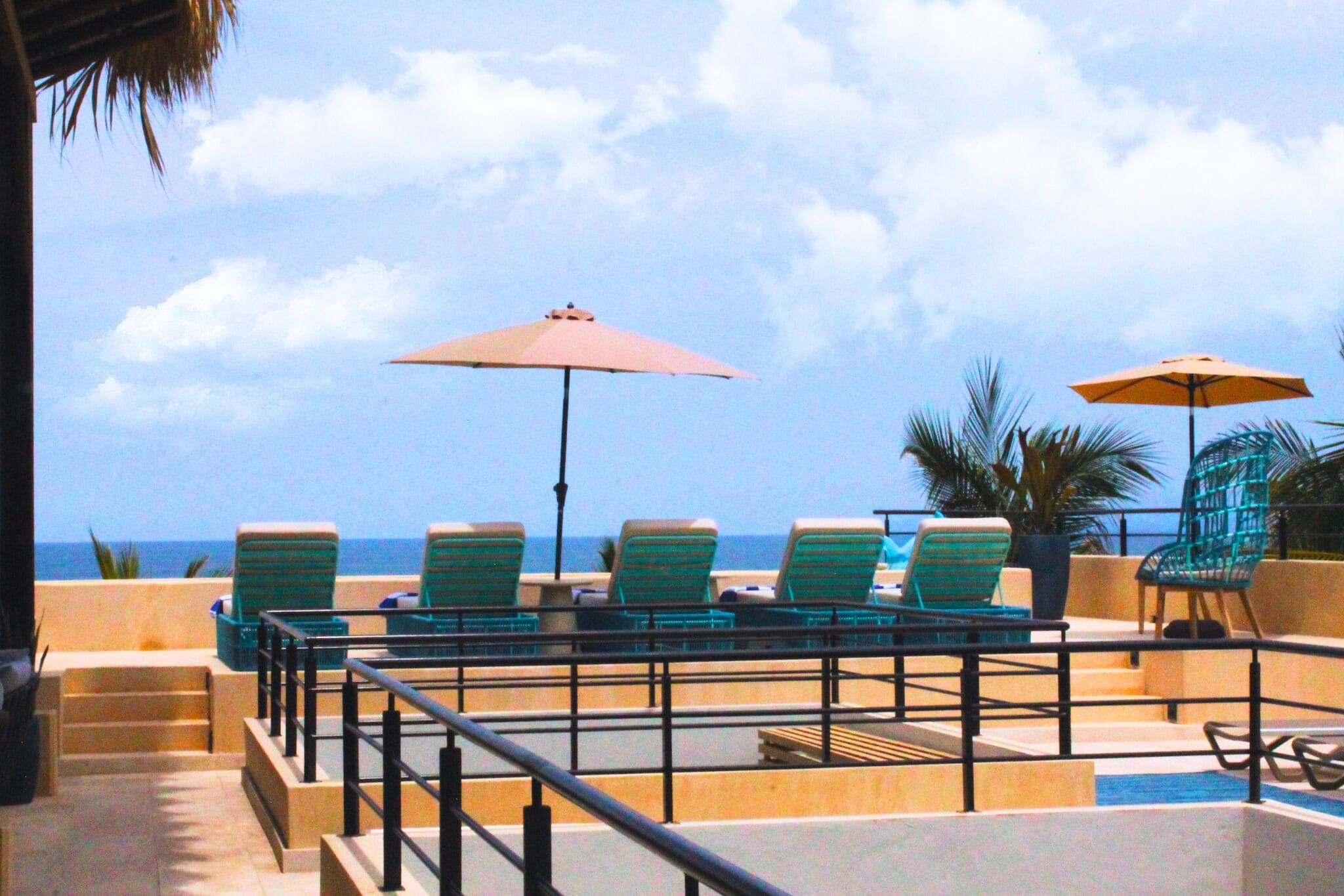 Zona de piscina con sillones y sombrillas, con vistas al océano.