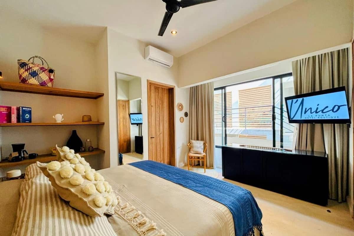 Una habitación de hotel con cama, televisor, escritorio y ventana con cortinas.