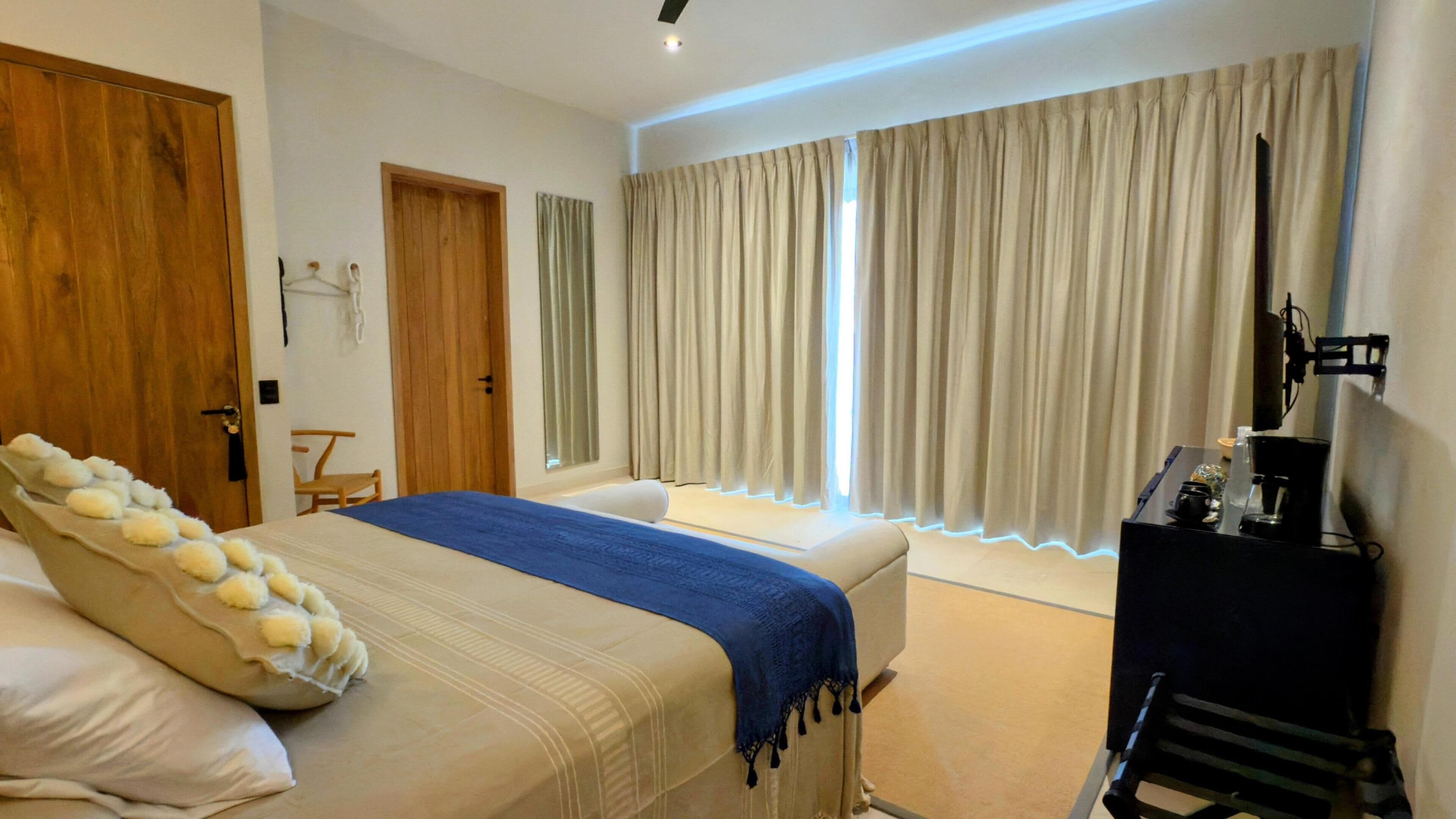 Une chambre à coucher comprenant un lit, un fauteuil de massage, un bureau avec une machine à café et une fenêtre avec des rideaux.