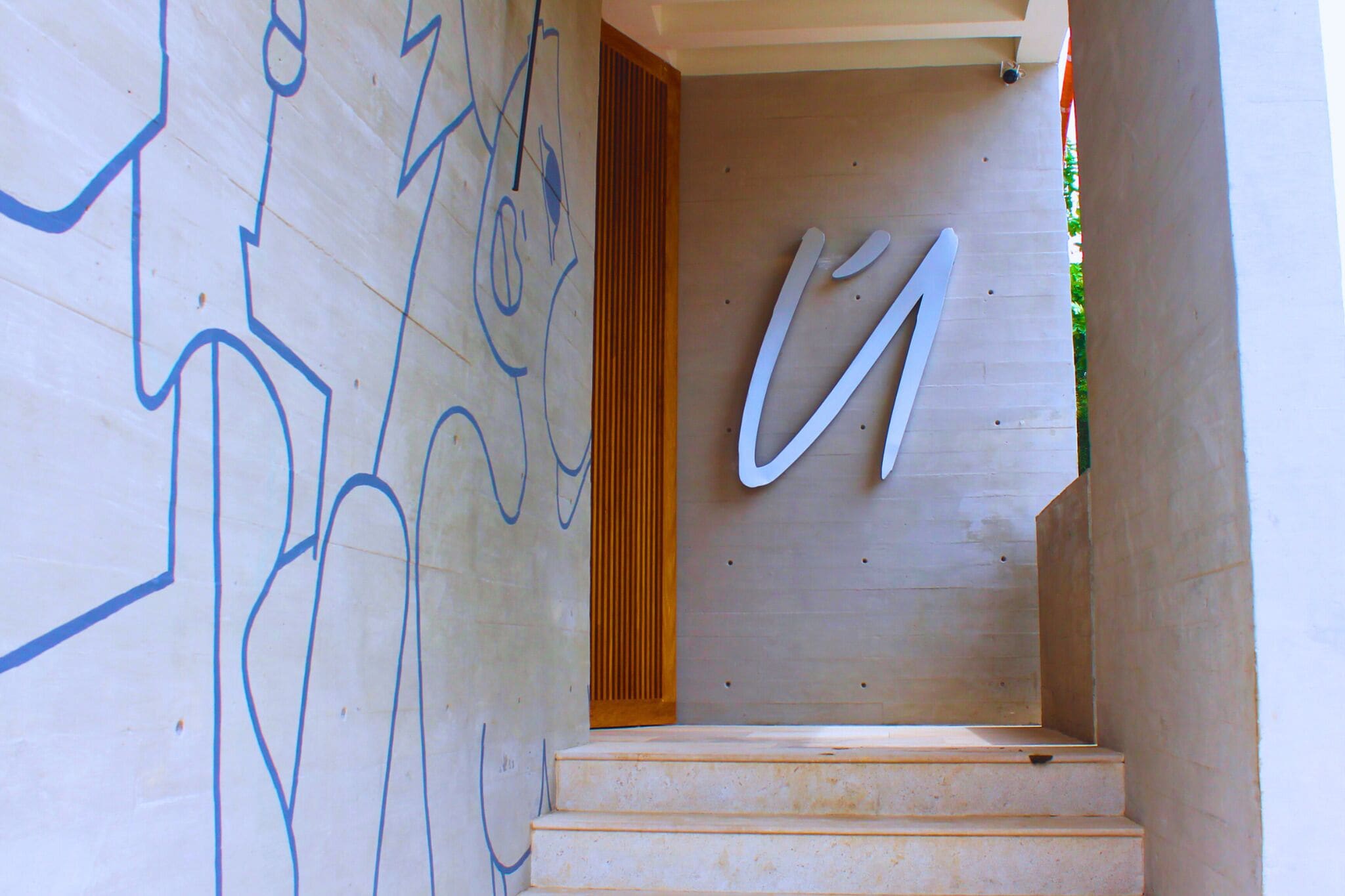 A staircase with a wooden handrail and a wall with abstract blue graffiti.