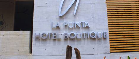 A sign for La Punta Hotel Boutique with a modern design and wooden slats on the right.