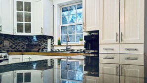 Una cocina moderna con armarios blancos, encimera negra y un ventanal grande.
