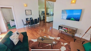 Una sala de estar moderna con una mesa de centro de madera, un sofá verde y un televisor montado en la pared.