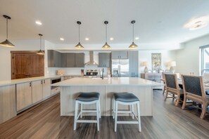 A modern kitchen with a central island, pendant lighting, and wooden cabinetry. - Columbia Falls Downtown Condo (Columbia Falls)