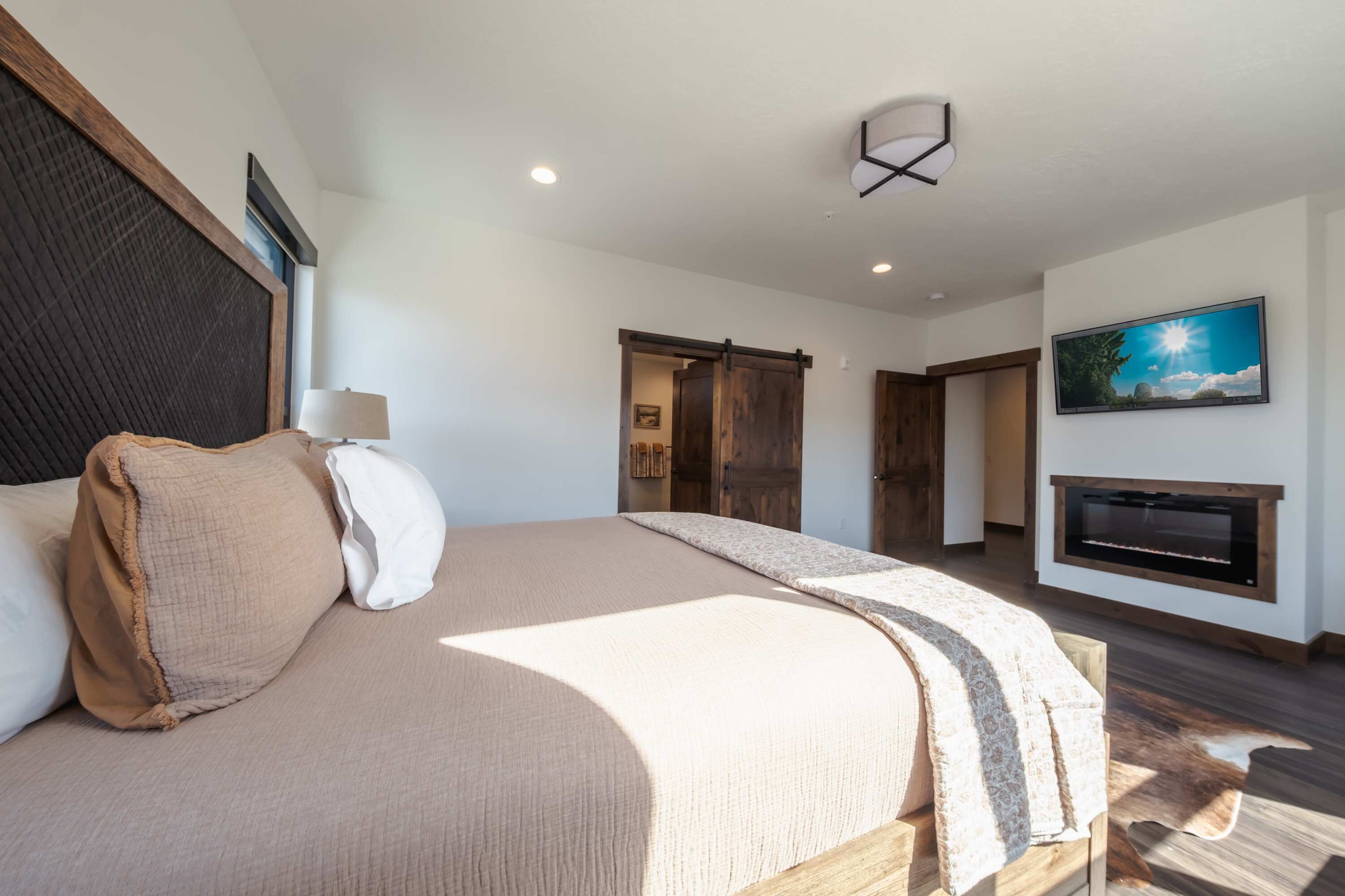 Un dormitorio con una cama grande, un televisor montado en la pared y una chimenea.