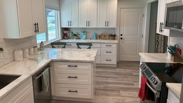 Una cocina moderna con armarios blancos, una isla grande y un horno empotrado.