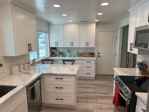 A modern kitchen with white cabinets, a large island, and a built-in oven.