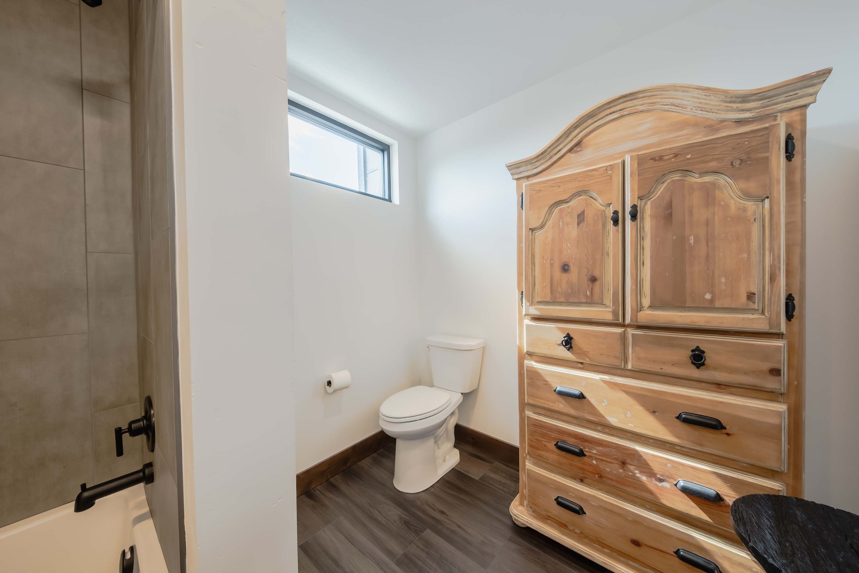 Un baño con un armario de madera, un inodoro y una bañera.