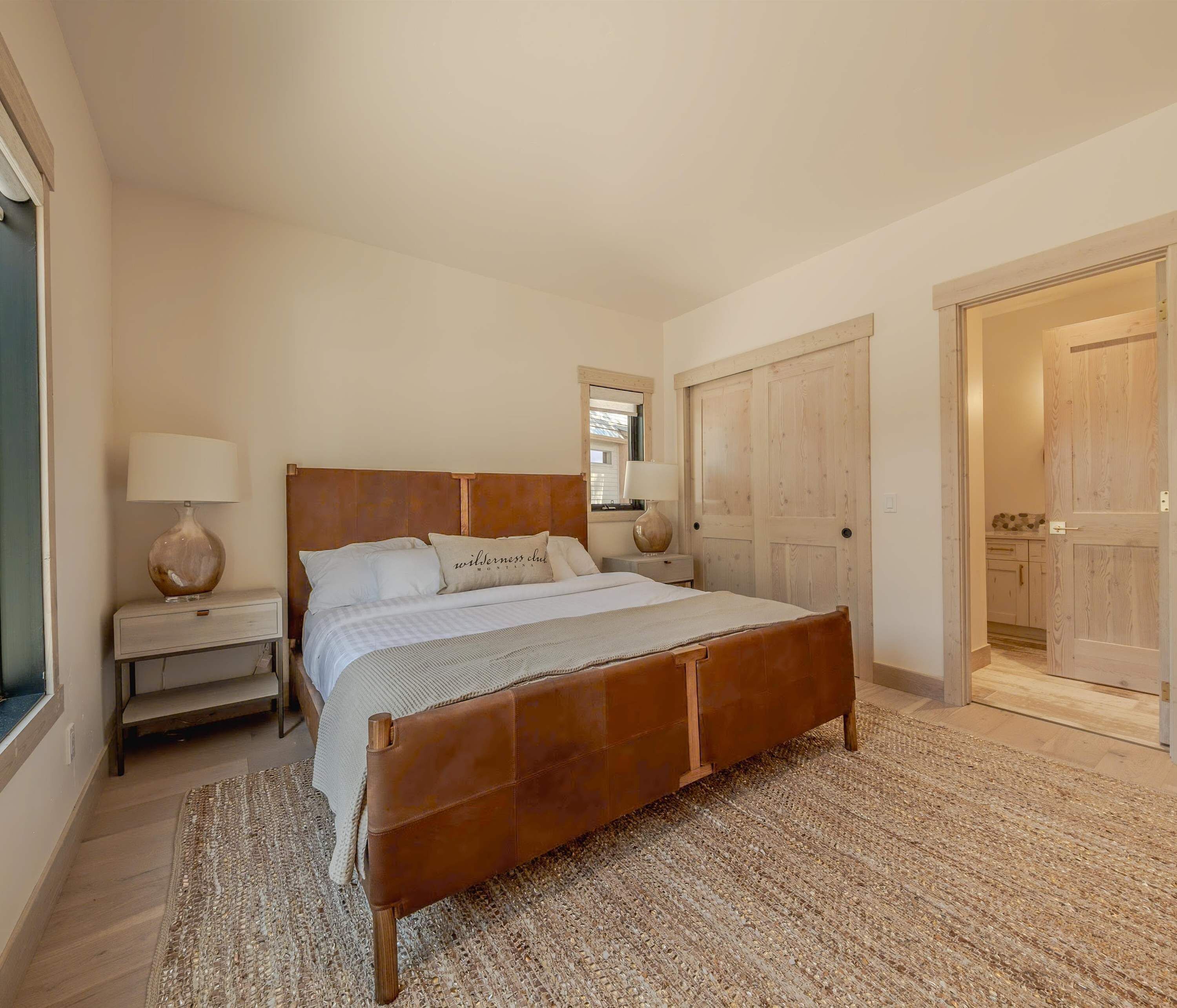 A bedroom with a wooden bed, bedside tables, a mirror, and a wardrobe.