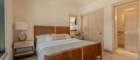 A bedroom with a wooden bed, bedside tables, a mirror, and a wardrobe.