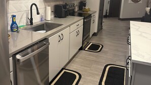 Eine moderne Küche mit Edelstahlgeräten, weißen Schränken und Teppichen in Schwarz und Beige.