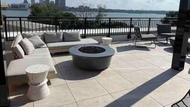 Eine Terrasse mit einer Couch, Stühlen und einer Feuerstelle.
