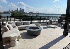 A terrace with a sofa, chairs, and a fire pit.