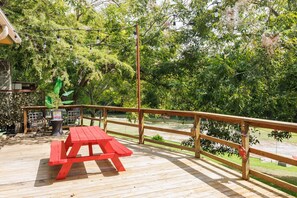 A wooden deck with a picnic table and a railing overlooking a body of water.