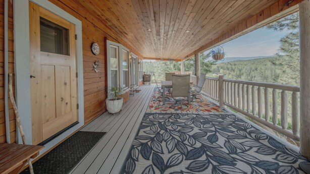 Une véranda en bois avec un banc, une table et un tapis.