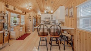 L’intérieur d’un chalet en bois comprend une cuisine, un coin repas et une grande fenêtre.