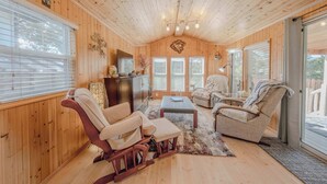 L’intérieur chaleureux d’un chalet avec des murs en bois, une cheminée, un canapé et une table à manger.