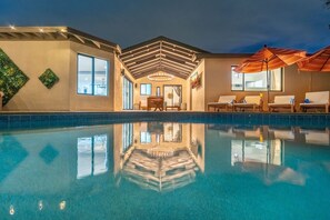 Una piscina con sillas de descanso y sombrillas, un patio techado y vista a la piscina.