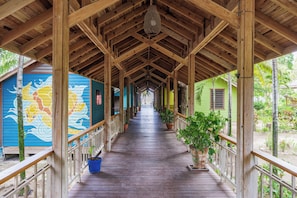 A covered wooden walkway with a view of colorful buildings and potted plants.