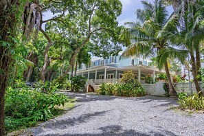 A house with a covered porch, surrounded by tropical vegetation.