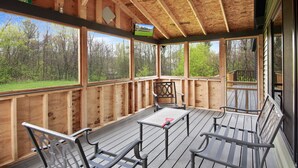 Una terrazza esterna coperta con ringhiere in legno, un tavolo e quattro sedie.