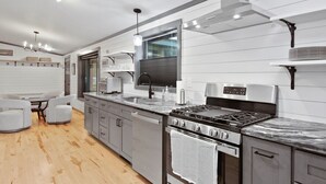Una cucina moderna con forno integrato, elettrodomestici in acciaio inossidabile e una zona pranzo in legno.