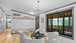 Un interno moderno con zona pranzo, tavolo rotondo e quattro sedie, un lampadario e un'ampia finestra con vista sull'esterno.