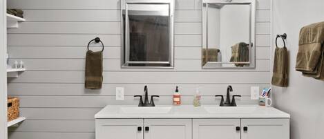 A bathroom with two sinks, a mirror, and overhead lighting.
