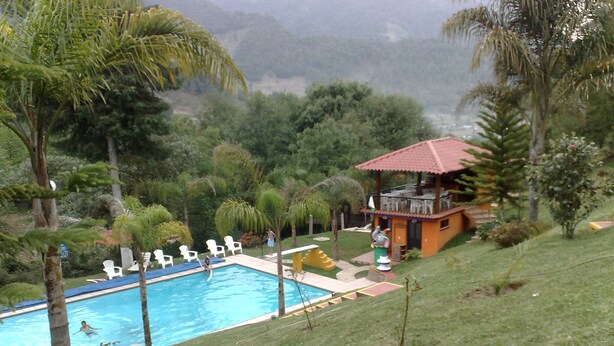 A swimming pool with lounge chairs, a small building with a red roof, and surrounding greenery. - OTRO ROLLO EN JILOTPEC ZACAPOAXTLA  (Zacapoaxtla)