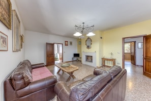 A living room with a brown leather sofa, a wooden coffee table, a fireplace, and a television.