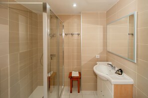 Un baño con cabina de ducha de vidrio, un lavamanos y un espejo.