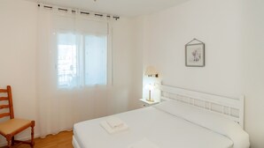 A hotel room with a bed, a chair, a bedside table with a lamp, and a window with curtains. - WELCS APARTAMENTO 260 EMP con vistas al canal (Empuriabrava)