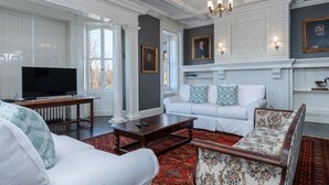 A living room with a white sofa, a patterned armchair, a television, and a fireplace. - Spacious 6-bedroom house with AC, WiFi in charming Springfield (Springfield)