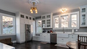 A kitchen with white cabinetry, a stainless steel refrigerator, and a wooden dining table. - Spacious 6-bedroom house with AC, WiFi in charming Springfield (Springfield)