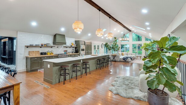 A spacious kitchen with a large island, bar stools, and a potted plant.