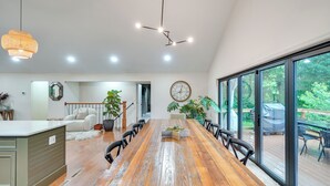 A spacious dining area with a wooden table, chairs, and a large window offering a view of the outdoors.