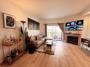 A living room with a sofa, a coffee table, a TV, and a fireplace. - Modern Condo heart of North Park-2Bed-2ba-Parking-Laundry-AC (San Diego)