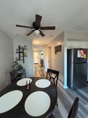 A modern kitchen with a built-in refrigerator, a dining table with placemats, and a ceiling fan.