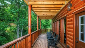 A wooden deck with a railing, a row of chairs, and a door. - Soak Among the Treetops, Swim Indoors, Shoot Pool & Host Luxe Movie Nights - Whispering Pines Escape (Sevierville)