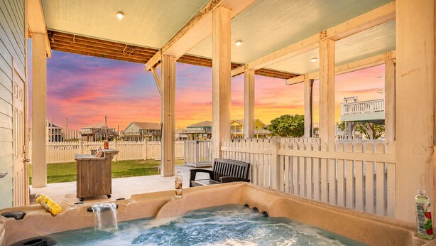 Ein Whirlpool mit Blick auf einen Sonnenuntergang, eine Holzterrasse und ein Zaun.
