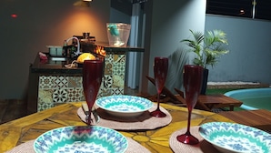 A dining area with a wooden table set for four, featuring patterned plates and red wine glasses. - Big House Leisure 🌊 (Dourados)