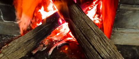 A cooking pot over an open flame with logs underneath.