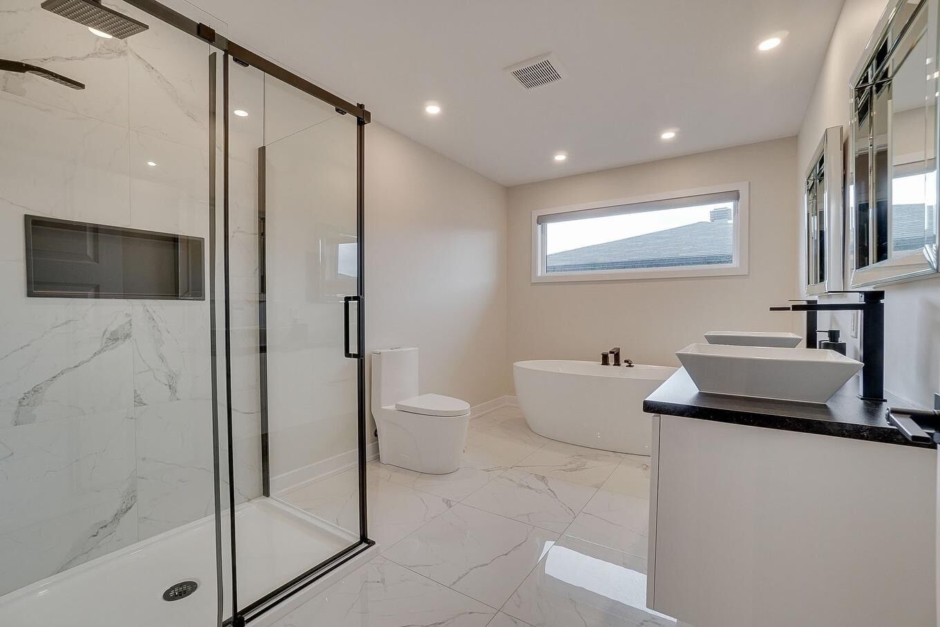 A modern bathroom with a glass-enclosed shower, a freestanding toilet, a freestanding bathtub, and a vanity with a sink.