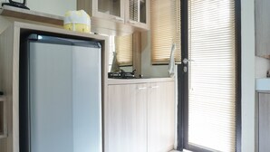 Eine Küche mit Kühlschrank, Holzschränken und einem Fenster mit Jalousien.