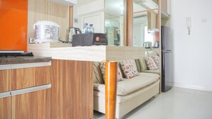 A compact kitchen with a wooden cabinet, a countertop, a kettle, and a refrigerator. - Homey And Strategic 2Br At Bassura City Apartment (Jakarta)