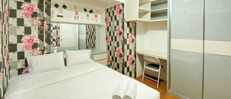 A hotel room with a bed, a desk, and a wardrobe.