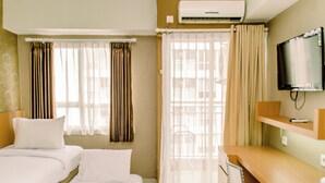 Una habitación de hotel con cama, escritorio, silla, aire acondicionado y televisor.