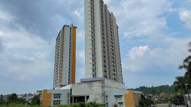 Two high-rise buildings with balconies, a clear sky, and some greenery in the foreground. - Homey And Nice Studio Cinere Bellevue Suites Apartment (Depok)